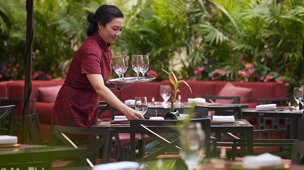 Server setting a table at Shanghai Terrace outdoor patio